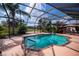 This screened pool area features tropical landscaping and an adjacent outdoor dining area with a BBQ grill at 2002 Palm View Rd, Sarasota, FL 34240