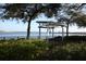 Waterfront view with covered swing, lush greenery, and bridge in the distance at 210 3Rd W St # 8204, Bradenton, FL 34205