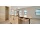 Kitchen island with a stainless steel dishwasher and sink, alongside view of the living space at 217 Potenza Loop, North Venice, FL 34275