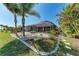 Secluded backyard featuring a screened lanai, lush landscaping, and a well-manicured lawn at 221 Fairway Rd, Rotonda West, FL 33947