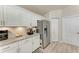 Modern kitchen features stainless steel refrigerator, sleek countertops, and ample storage space with white cabinetry at 221 Fairway Rd, Rotonda West, FL 33947