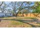 Backyard with wooden fence, mature trees, lush lawn, and white home at 2300 23Rd S St, St Petersburg, FL 33712