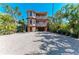 Beautiful three-story home featuring lush landscaping and a spacious paved driveway at 2306 Canasta Dr, Bradenton Beach, FL 34217