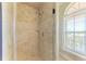 Shower stall with beige tile, glass door, and window with blinds at 2306 Canasta Dr, Bradenton Beach, FL 34217