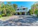 Inviting two-story home features lush landscaping, a welcoming front porch, and a spacious driveway at 2308 Canasta Dr, Bradenton Beach, FL 34217