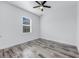 Neutral bedroom with wood-look flooring, a ceiling fan, and a window overlooking the backyard at 28960 Gin Ln, Punta Gorda, FL 33982
