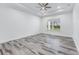 Neutral bedroom featuring wood-look floors, a ceiling fan, tray ceiling, and a window overlooking a backyard at 28960 Gin Ln, Punta Gorda, FL 33982