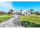 Beautifully landscaped single-story home with a long brick driveway and bright blue sky at 28960 Gin Ln, Punta Gorda, FL 33982