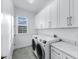 Bright laundry room with modern washer/dryer, white cabinets and marble countertops at 28960 Gin Ln, Punta Gorda, FL 33982