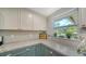 Granite countertops and white cabinets by window featuring plants add style to this charming kitchen at 3278 Village Green Dr # 1024, Sarasota, FL 34239