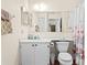 Well-lit bathroom with white vanity, toilet, mirror, and decorative seashell shower curtain at 3300 Loveland Blvd # 3203, Punta Gorda, FL 33980