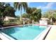 Community pool is surrounded by lush landscaping, a metal fence, and lounge chairs for relaxing by the water at 3523 Longmeadow # 12, Sarasota, FL 34235