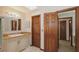 Bathroom features a light vanity with a granite countertop, storage and wood doors at 3837 Torrey Pines Blvd, Sarasota, FL 34238