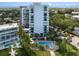 Aerial view of a modern condo building with a pool, lush landscaping, and parking at 4822 Ocean Blvd # 2D, Sarasota, FL 34242