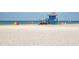 Scenic view of a white sandy beach featuring a blue lifeguard stand and beachgoers enjoying the day at 4822 Ocean Blvd # 2D, Sarasota, FL 34242