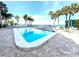 Beautiful community pool with brick patio, palm trees, and ocean view under clear blue skies at 4822 Ocean Blvd # 2D, Sarasota, FL 34242