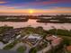 An aerial view of a waterfront property at sunset, showing the house, waterway access, and surrounding nature at 525 S Shore Dr, Osprey, FL 34229
