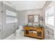 Bright bathroom with a glass shower, toilet, and wooden cabinet with a glass countertop and dual sinks at 525 S Shore Dr, Osprey, FL 34229