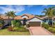 Charming single-story home with a tile roof, manicured landscaping, and a brick paver driveway at 5946 Caspian Tern Dr, Sarasota, FL 34238