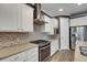 Gourmet kitchen featuring stainless steel appliances, granite countertops, tile backsplash, and white cabinetry at 5946 Caspian Tern Dr, Sarasota, FL 34238