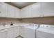 Laundry room with white cabinets, utility sink, and modern washer and dryer at 5946 Caspian Tern Dr, Sarasota, FL 34238