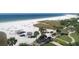 Enjoy this aerial beach view with clear turquoise waters, white sand, and charming beachside structures at 6140 Midnight Pass Rd # B6, Sarasota, FL 34242