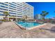 The brick-paved pool area offers a tranquil escape under a clear sky with access to the high-rise building at 6140 Midnight Pass Rd # B6, Sarasota, FL 34242