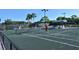 Players on green tennis courts with lighting, landscaping, and covered seating area at 8755 Olde Hickory Ave # 7204, Sarasota, FL 34238