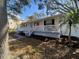 Cozy home featuring a charming white porch, neutral siding, mature landscaping, and a private setting at 916 Michigan Ave, Palm Harbor, FL 34683