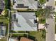 An aerial view showcasing the property's roof, screened-in pool, lush landscaping, and proximity to the neighborhood street at 10030 Reagan Dairy Trl, Bradenton, FL 34212