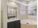 Bright bathroom featuring a large mirror, soaking tub, neutral tile and plantation shutters at 10030 Reagan Dairy Trl, Bradenton, FL 34212