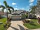 Charming home featuring a brick driveway, well-maintained lawn, lush landscaping, and mature palm trees at 10030 Reagan Dairy Trl, Bradenton, FL 34212