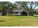 Exterior home view featuring mature trees, a covered porch, and lush landscaping at 1228 Wagon Wheel Dr, Sarasota, FL 34240