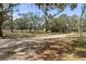 Large, well-maintained land with mature trees and a gravel driveway at 1228 Wagon Wheel Dr, Sarasota, FL 34240