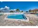 Community pool with a clear blue water, surrounded by lounge chairs and a paved deck on a sunny day at 13575 Martha Ave, Port Charlotte, FL 33981