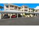Luxurious condominium building featuring covered parking and well-maintained landscaping under a clear blue sky at 2424 Placida Rd # C104, Englewood, FL 34224
