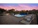 Community pool with brick paver patio, lounge chairs, and nearby pond with fountain, all under a beautiful sunset sky at 2720 60Th Avenue W Dr # D, Bradenton, FL 34207