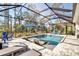The screened pool features in-pool loungers and seating with lush landscaping outside the enclosure at 2877 Sultan Ct, North Port, FL 34286