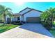 Well-maintained single-Gathering home with mature landscaping, brick driveway, and two-car garage at 324 Whispering Palms Ln, Bradenton, FL 34212