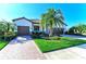 Inviting single-Gathering home featuring a lush front yard, brick driveway, and two-car garage at 324 Whispering Palms Ln, Bradenton, FL 34212