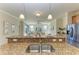 A modern kitchen island with stainless steel sink, granite countertop, and stainless refrigerator in background at 324 Whispering Palms Ln, Bradenton, FL 34212