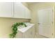 Bright laundry room featuring white washer/dryer, cabinets, and a charming decorative Laundry Inc. accent piece at 324 Whispering Palms Ln, Bradenton, FL 34212