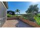 Paver patio surrounded by lush landscaping, offering picturesque views of the lake and swaying palm trees at 324 Whispering Palms Ln, Bradenton, FL 34212