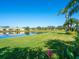 Picturesque lakefront property with an expansive lawn and serene water reflecting the homes and clear sky at 4155 Cascade Falls Dr, Sarasota, FL 34243