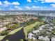 Wide aerial view of a residential community featuring lakes, golf course, trees, and nearby commercial districts under blue skies at 5552 Bentgrass Dr # 7-116, Sarasota, FL 34235