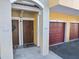 Inviting condominium entrance with two front doors, a brown door on the left and a red garage door on the right at 5552 Bentgrass Dr # 7-116, Sarasota, FL 34235
