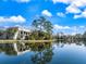 Exterior view of the condo with a red tile roof reflected on the peaceful lake and clear blue sky at 5552 Bentgrass Dr # 7-116, Sarasota, FL 34235