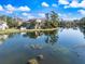 Scenic waterfront view featuring a condo building with a red tile roof reflecting on the tranquil lake at 5552 Bentgrass Dr # 7-116, Sarasota, FL 34235
