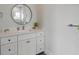 Bathroom with a white vanity, round mirror, and cabinet storage at 624 N Point Dr, Holmes Beach, FL 34217