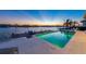 Sunset view from the waterfront pool with dock and outdoor seating in coastal home at 624 N Point Dr, Holmes Beach, FL 34217